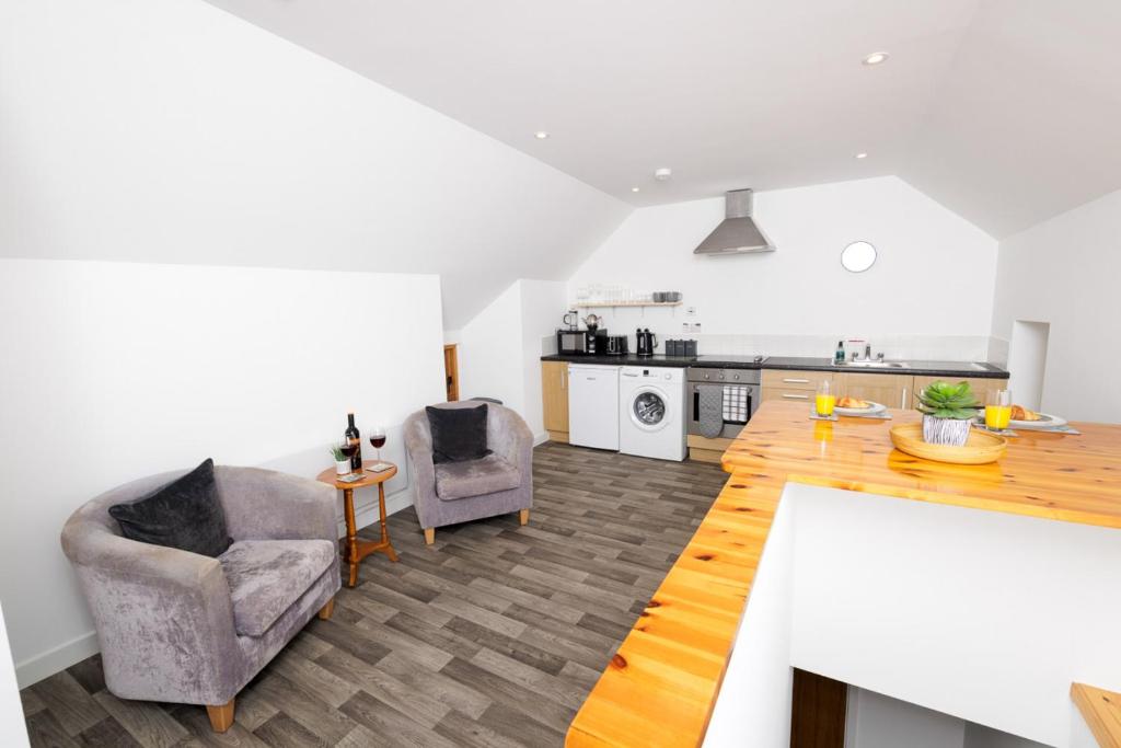 a living room with two chairs and a kitchen at Mowbray's Nook, Shetland Islands in Lerwick