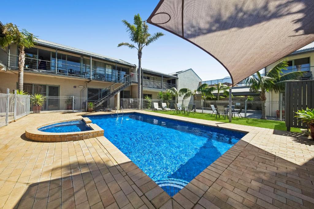 a swimming pool with a blue umbrella on top of it at Moonlight Bay Apartments in Rye