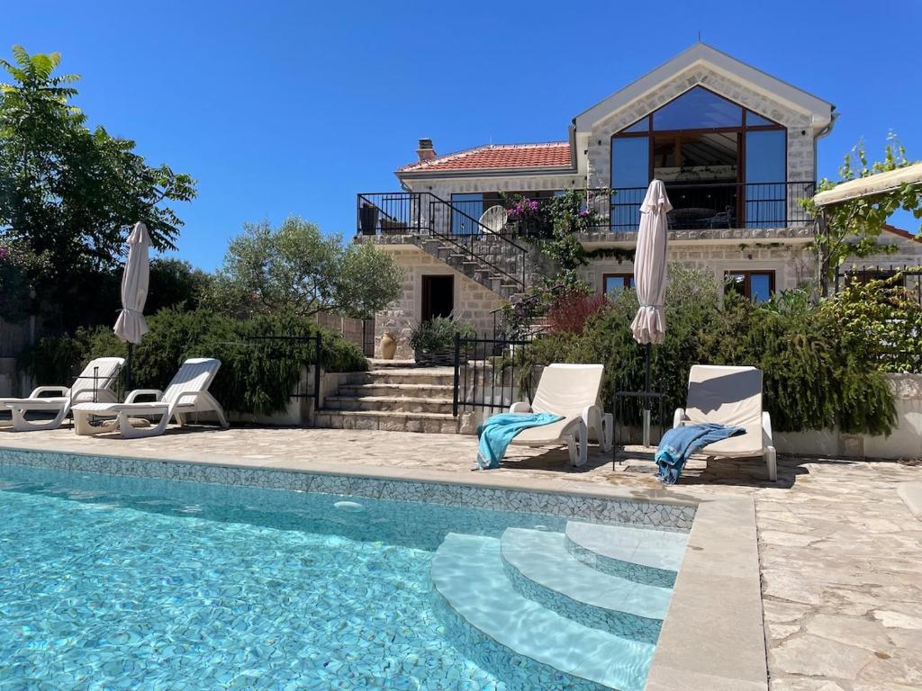 a villa with a swimming pool and chairs and a house at Perfect destination !!! in Ðuraševići