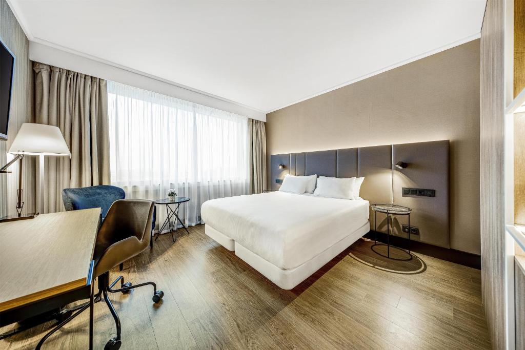 a hotel room with a bed and a desk at NH Brussels Airport in Diegem