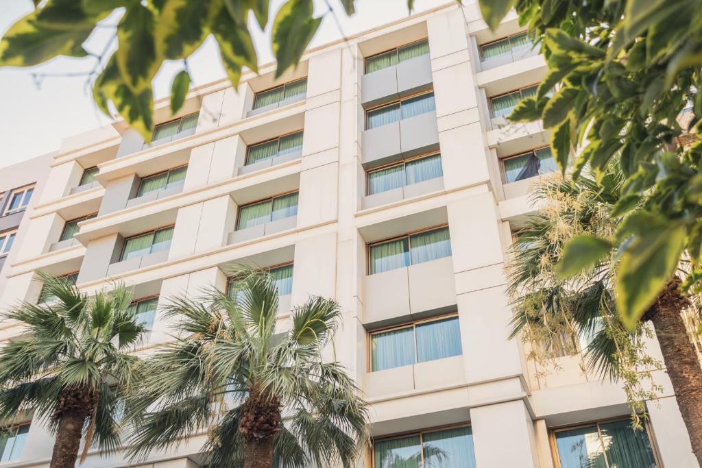 a building with palm trees in front of it at Heykel Suites Otel in Konak