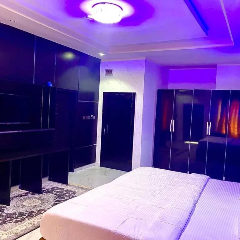 a bedroom with a white bed and a purple ceiling at Laycon hotel and suites in Ikuata