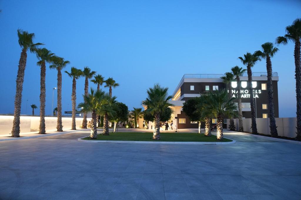 a row of palm trees in front of a building at UNA Hotels La Martella Matera in Matera