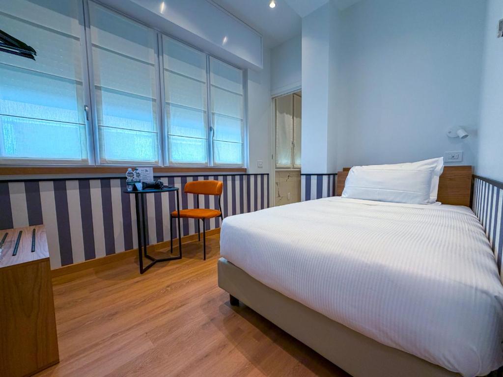 a bedroom with a white bed and a chair at HÕMA Certosa District in Milan