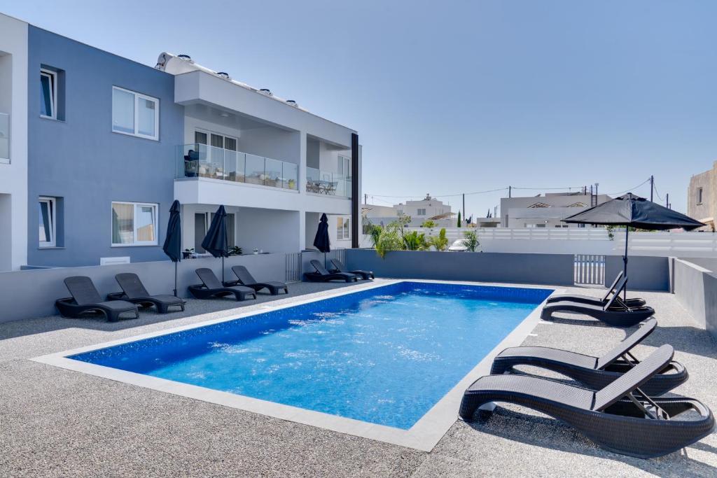 a swimming pool with chairs and an umbrella on a building at Oasis Luxury Residence B101 - Pool View in Xylophaghou