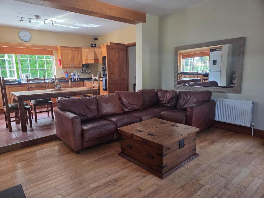 a living room with a brown couch and a table at Lawnside Retreat in Mullinavat