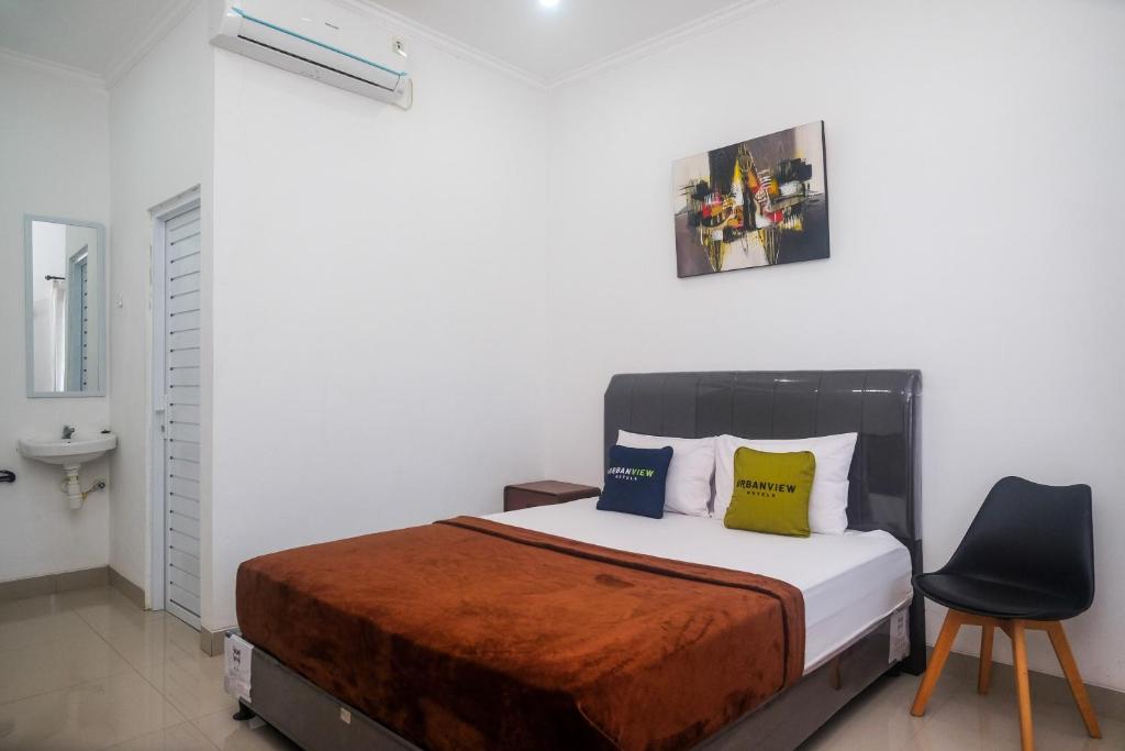 a bedroom with a bed and a chair at Urbanview keTemon Hotel & Resto YIA by RedDoorz in Yogyakarta