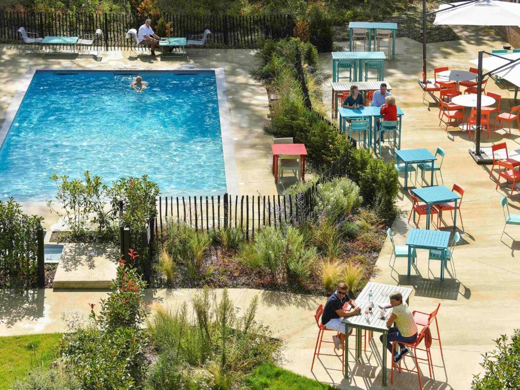 an overhead view of a pool with people sitting at tables at Novotel Wavre Brussels East in Wavre