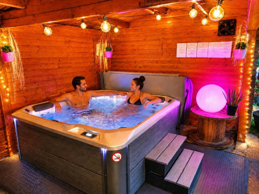 a man and woman in a hot tub in a room at Le Rensy in Ferrières