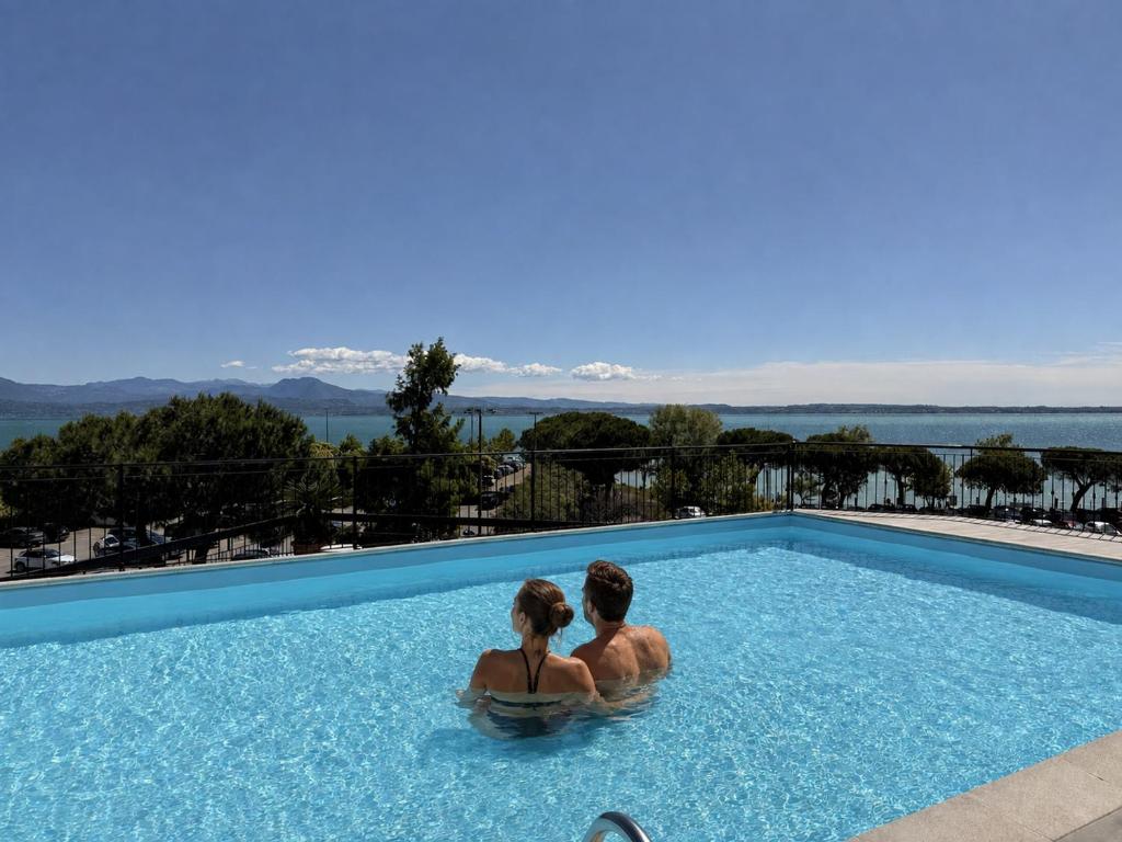 a man and a woman sitting in a swimming pool at Alevic Hotel Sirmione in Sirmione