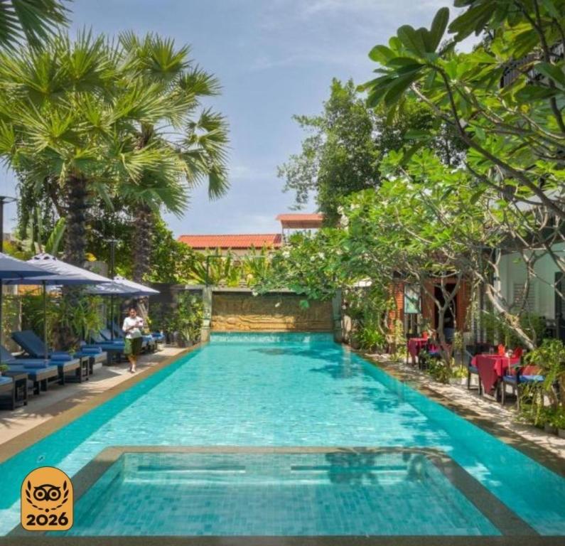 a swimming pool in a resort with palm trees at Khmer Mansion Boutique Hotel in Siem Reap