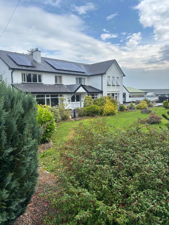 a large white house with a yard with bushes at Arch House in Florencecourt