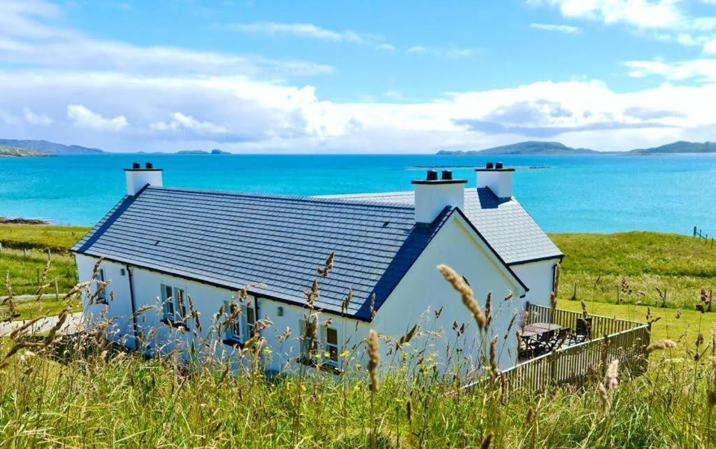 a house on the beach with the ocean behind it at Crofters Cottage Barra 