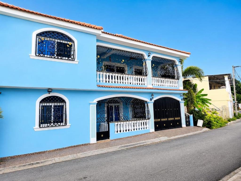 a blue house with a balcony on a street at Spacious Home with Private Pool in San Felipe de Puerto Plata