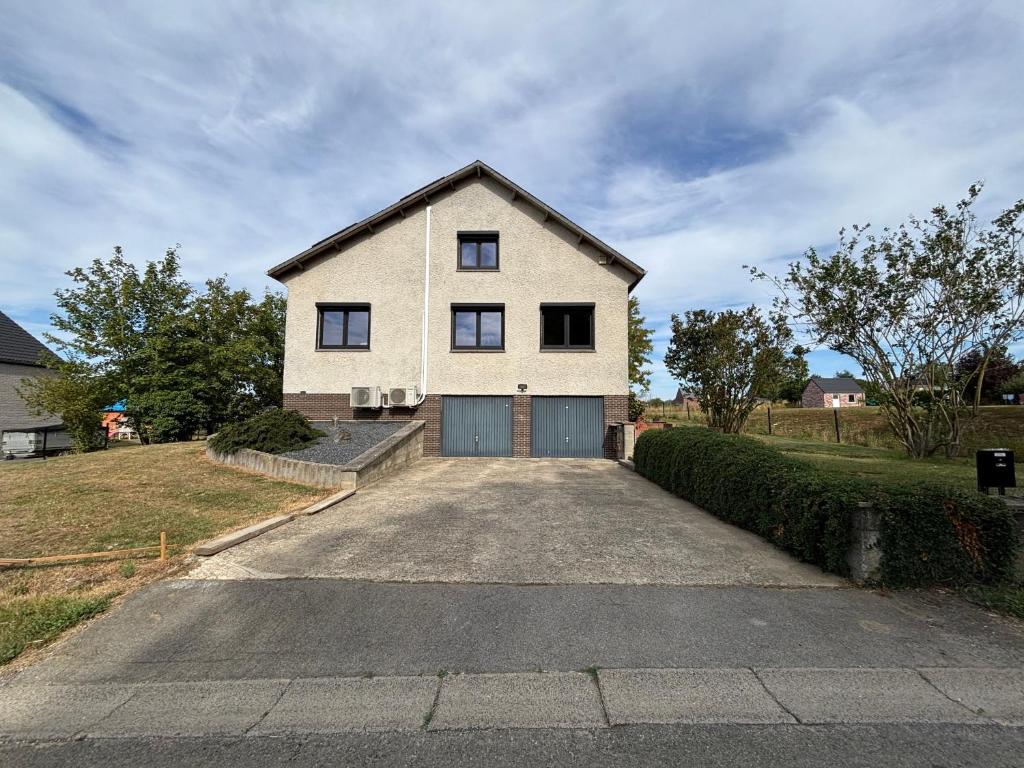 a white house with a garage on a driveway at Le Gîte du Trieux - Berzée in Berzée