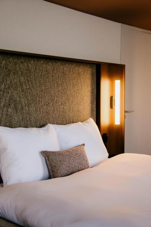 een bed met witte kussens in een hotelkamer bij Hotel Vrythof - just a room - digital key by email or SMS in Maastricht