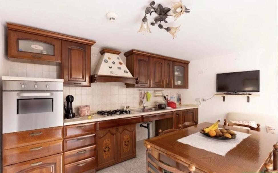 a kitchen with wooden cabinets and a bowl of fruit on a table at la casa rossa in Suni
