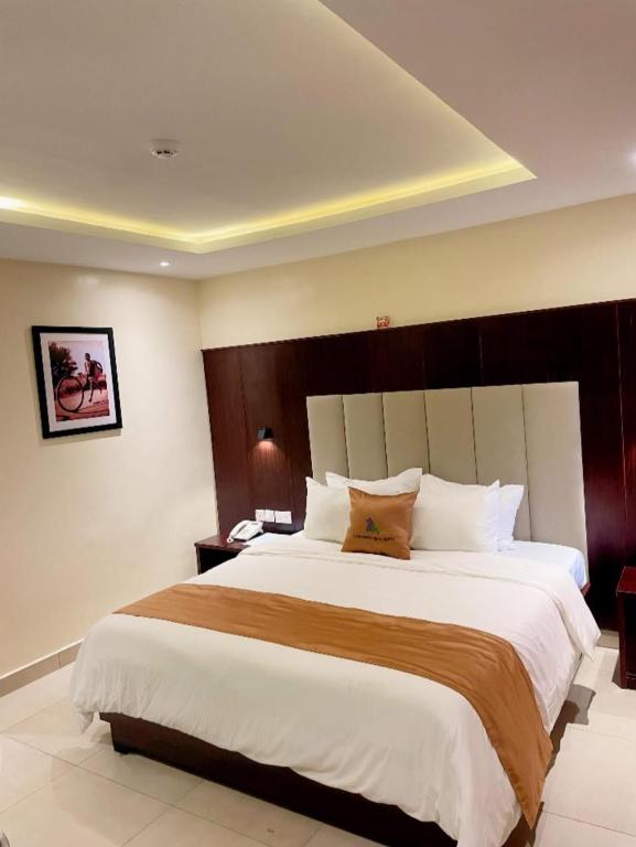 a bedroom with a large white bed with a wooden headboard at Lagos Airport Hotel in Ikeja