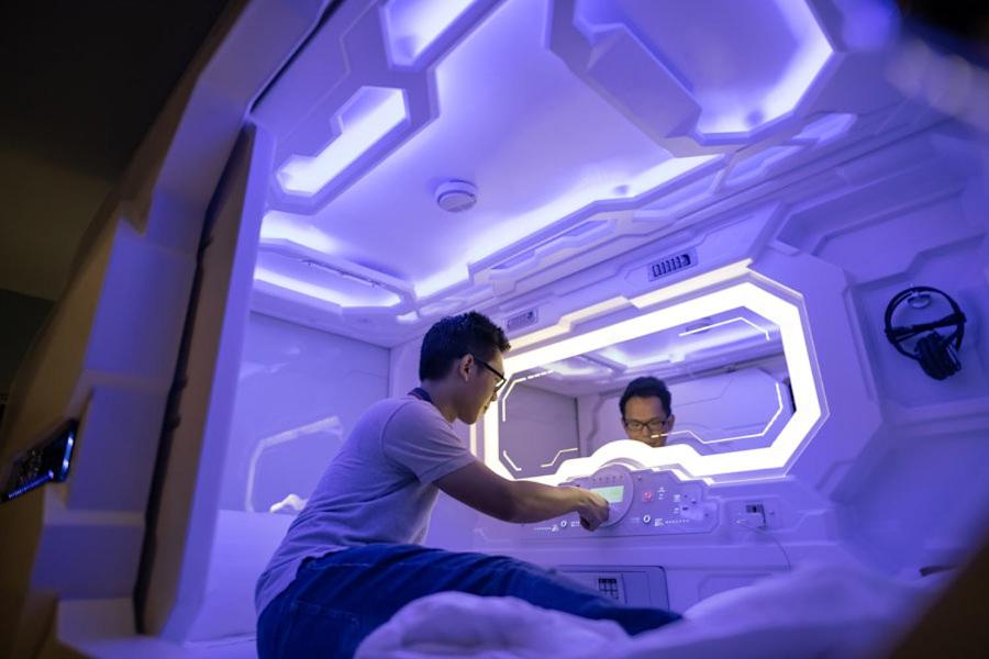 a man sitting in a room with a machine at Space Hotel KL Sentral in Kuala Lumpur