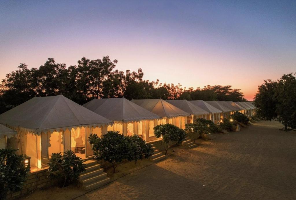 a row of white tents with trees and the sunset at Oran Desert camp & Resort in Sām