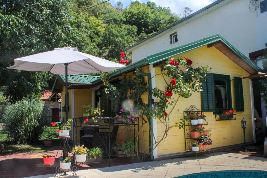 a yellow house with an umbrella and flowers at Pension Lale in Peštani