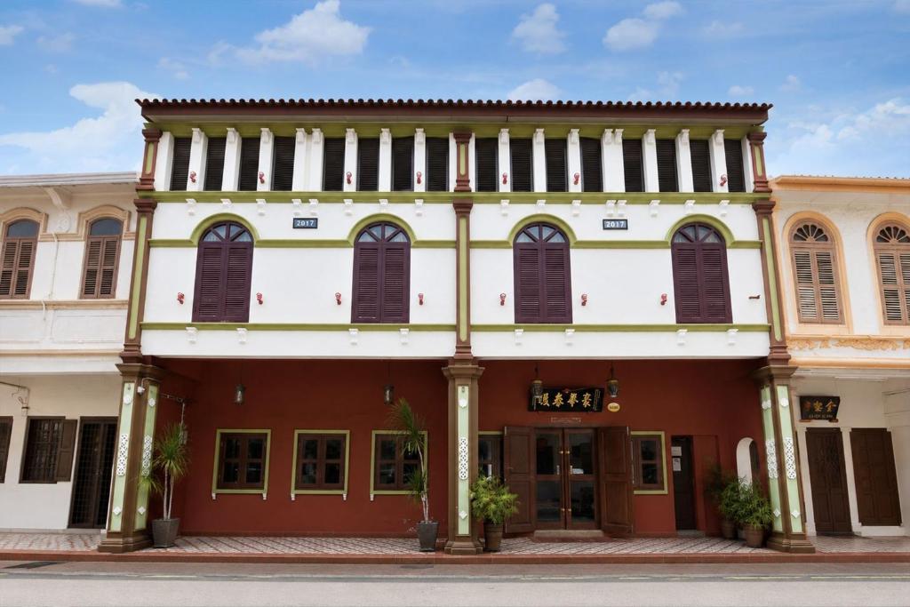 an old building with brown shutters on a street at Swiss Heritage Boutique Hotel Jonker Street Melaka in Malacca