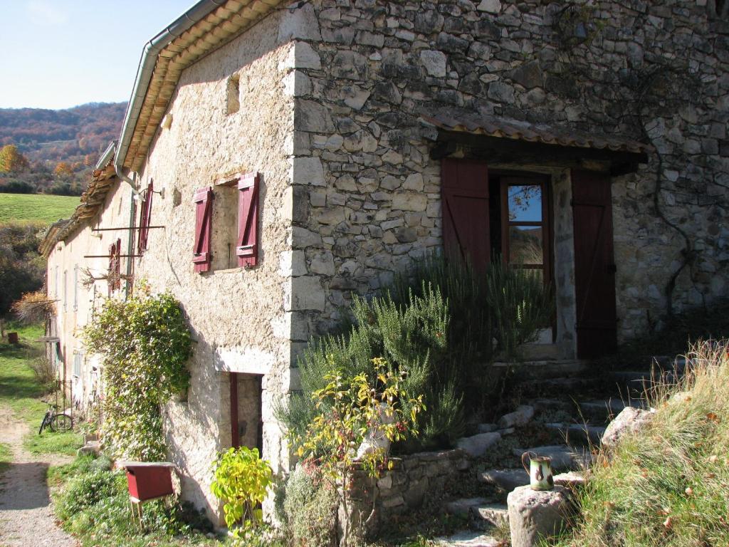 an old stone house with red shutters on it at Les Granges in Bouvières