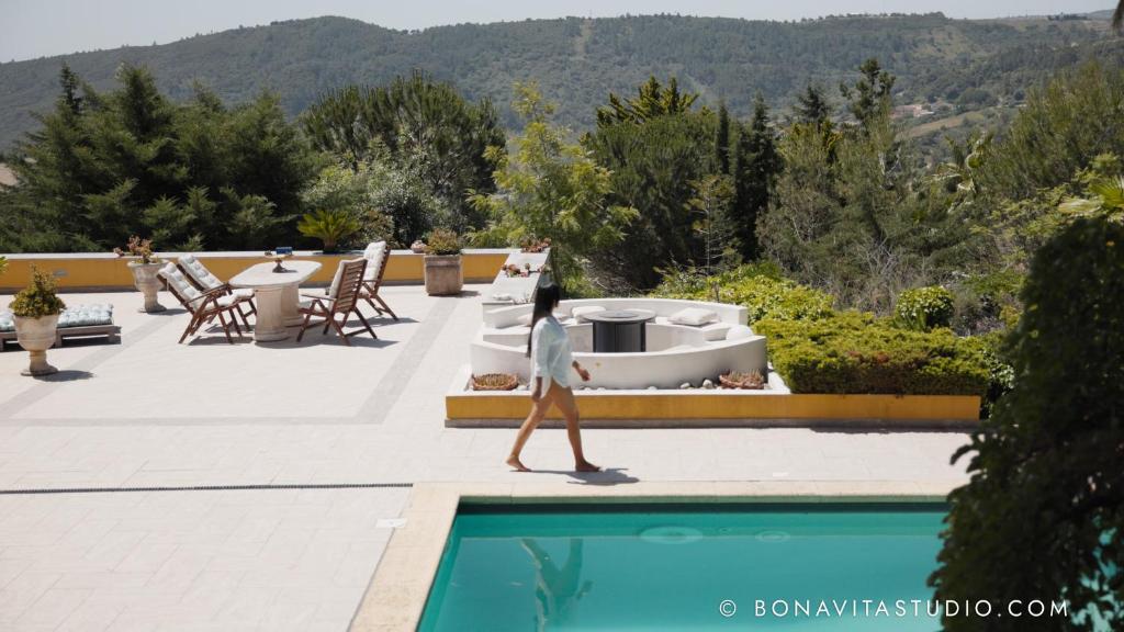a woman walking next to a swimming pool at Chambre aux Miroirs - La Vénus de Lisbonne in Calhandriz