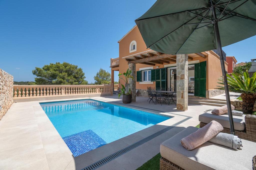 a villa with a swimming pool and an umbrella at Villas2meet Los Geranios in Cala Romàntica