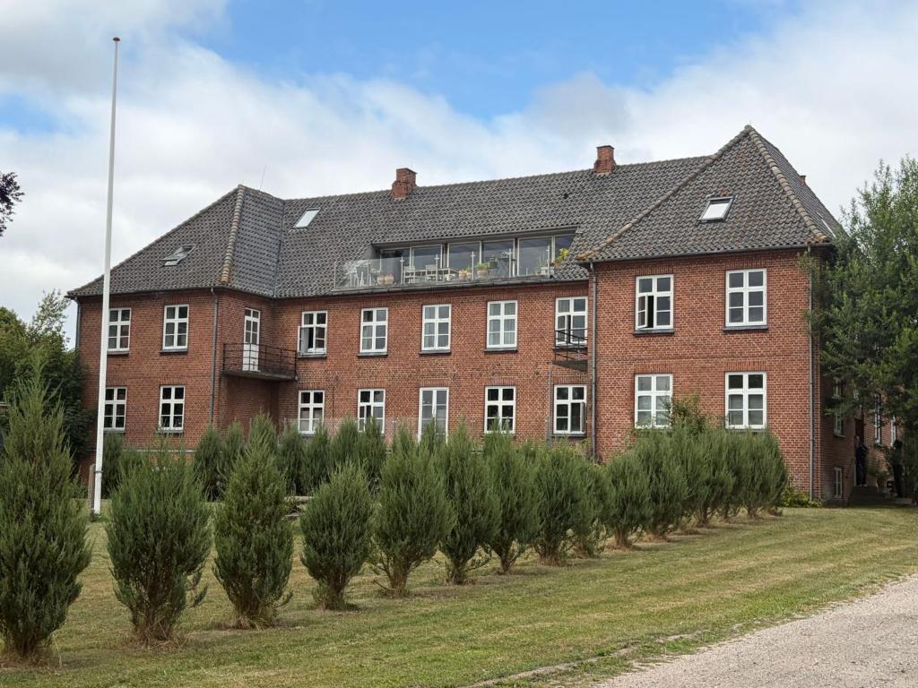 a large brick building with a row of trees in front at Roholtegaard in Faxe