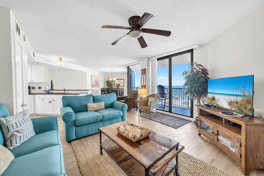 a living room with a blue couch and a ceiling fan at Aquavista 304W in Panama City Beach