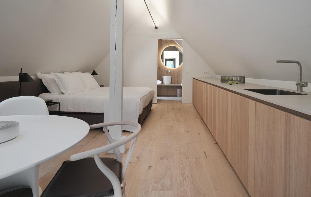 a bedroom with a bed and a kitchen with a sink at Het Wagenhuis bij Het Witte Kasteel in Loon op Zand