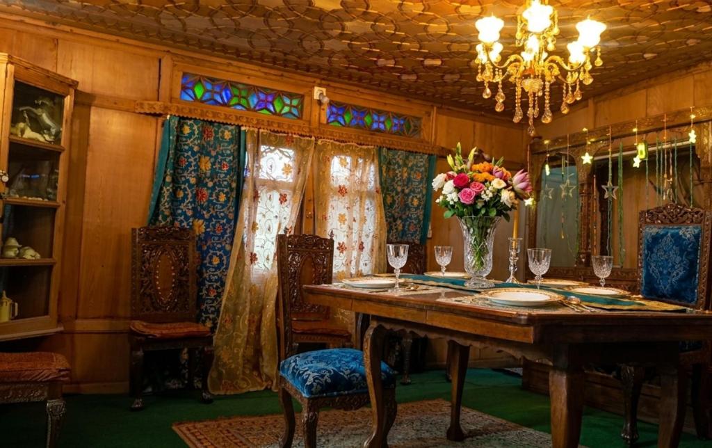 a dining room with a table and chairs and a chandelier at Kashmir View group of Houseboat in Srinagar
