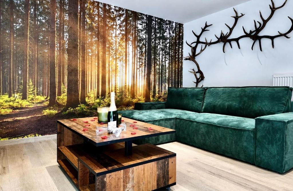 a living room with a green couch and a forest mural at Eh ma biche in Stoumont