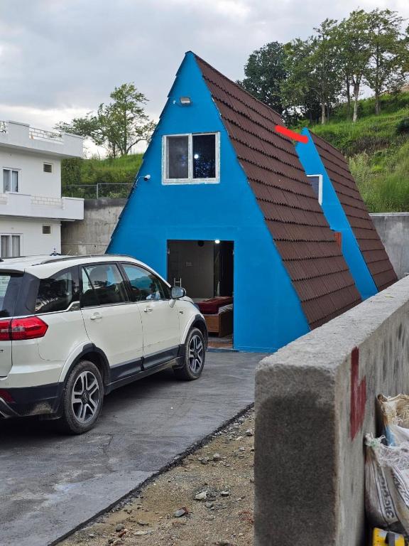 a blue house with a car parked in front of it at Monal Nests in Champawat