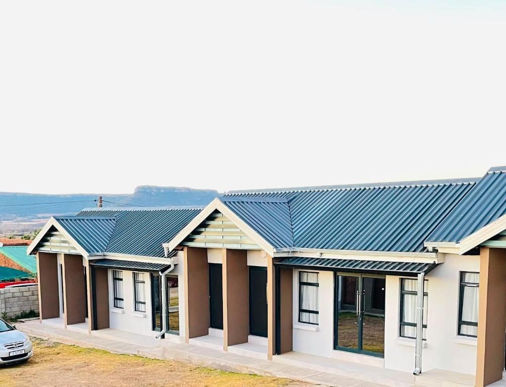 a row of houses with a blue roof at MAISON MOSH ll GUEST HOUSE in Maseru