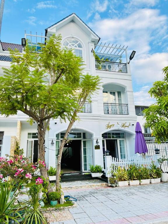 a white house with a tree in front of it at Happy House in Cam Lâm