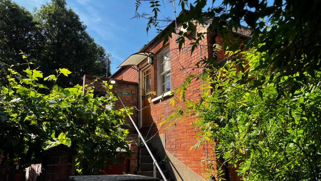 a red brick building with a window and trees at Mews Apartments in Lincoln