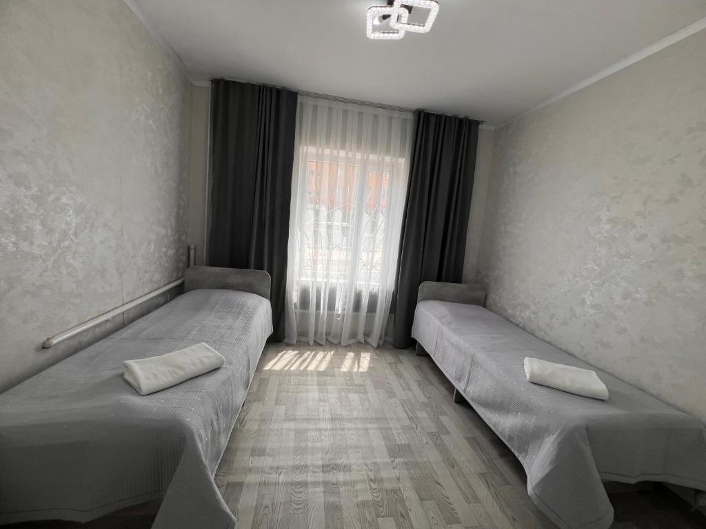 a room with two beds in front of a window at Altyn Sandyk in Karakol