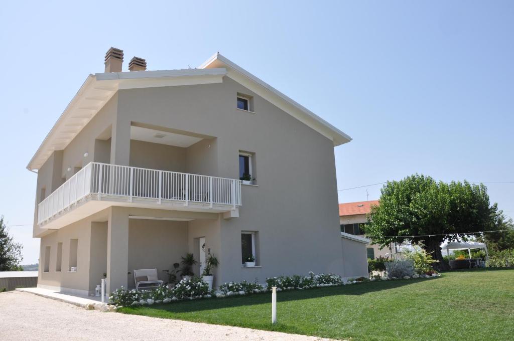 a white house with a lawn in front of it at Dolce Conero Guest House in Camerano