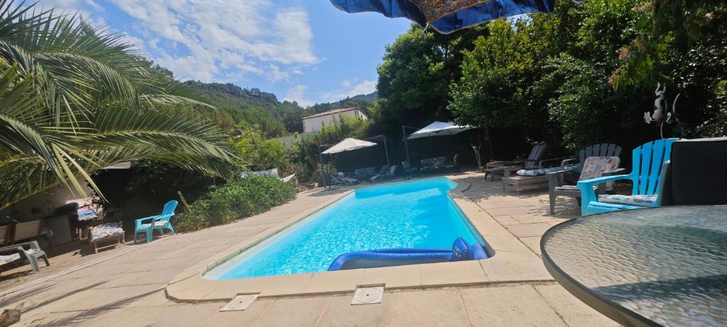 a swimming pool with blue chairs and a table at Gîte effet d’art in Saint-Privat