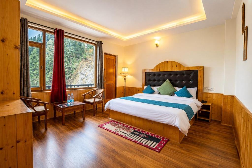 a bedroom with a bed and a desk and a window at Hotel Biker Gang Hotel & Cafe in Kyelang