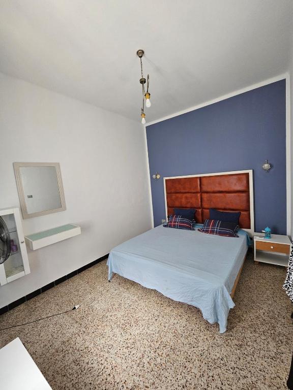 a bedroom with a bed with a blue wall at Furnished accommodation S2 in Nabeul in Nabeul