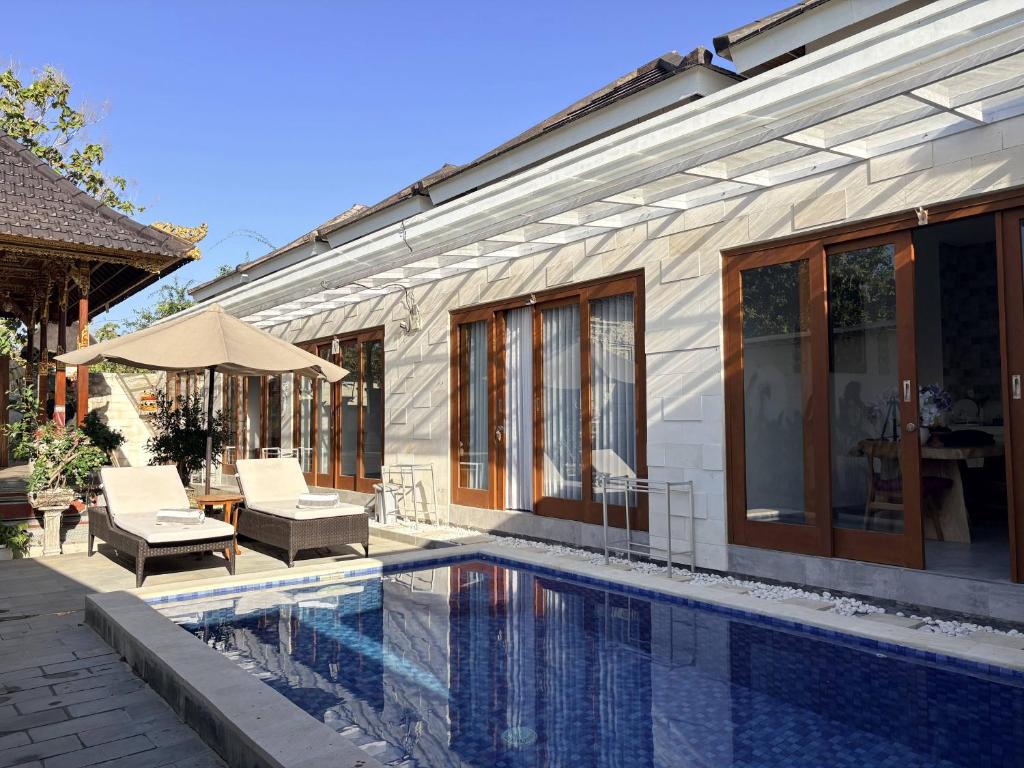 a house with a swimming pool next to a building at Amy Guesthouse Nusa Dua in Nusa Dua