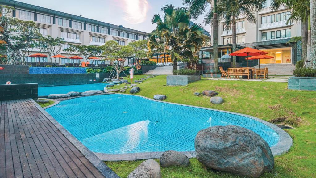 a swimming pool in front of a building at HARRIS Hotel & Conventions Malang in Malang