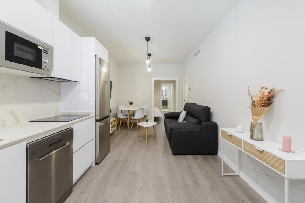 a kitchen and living room with a couch and a table at Torrejón Suites in Torrejón de Ardoz