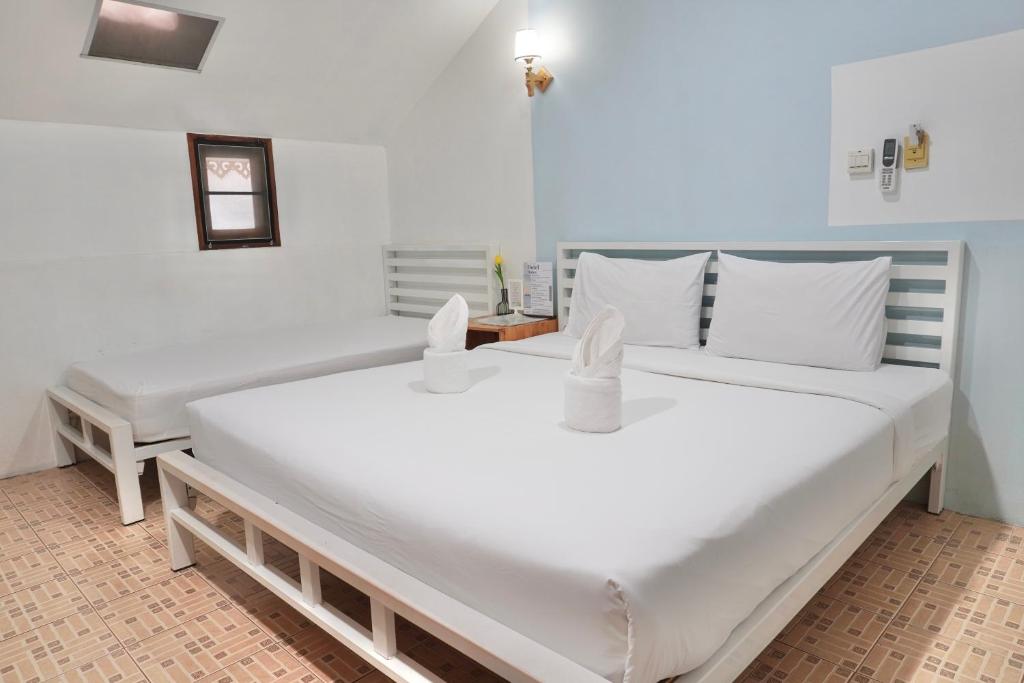 two large white beds in a room with a table at Khun Ying House in Ko Tao