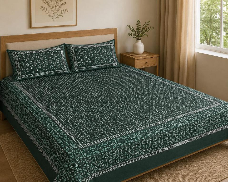 a bed with a green comforter and pillows at Hotel Lomontreey in Kākori