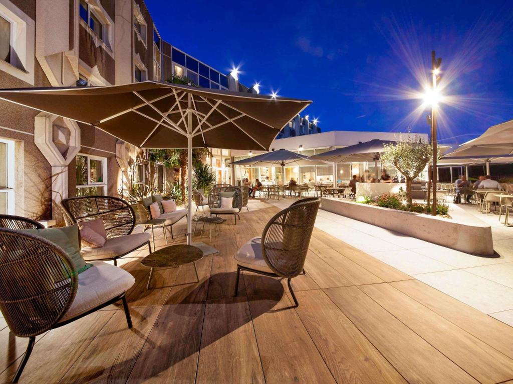 an outdoor patio with chairs and an umbrella at Novotel Clermont-Ferrand in Clermont-Ferrand