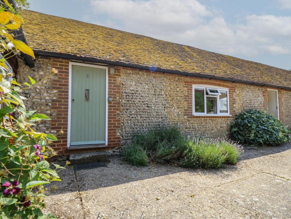 a brick house with a green door and some plants at Byre Cottage 3 in Pulborough